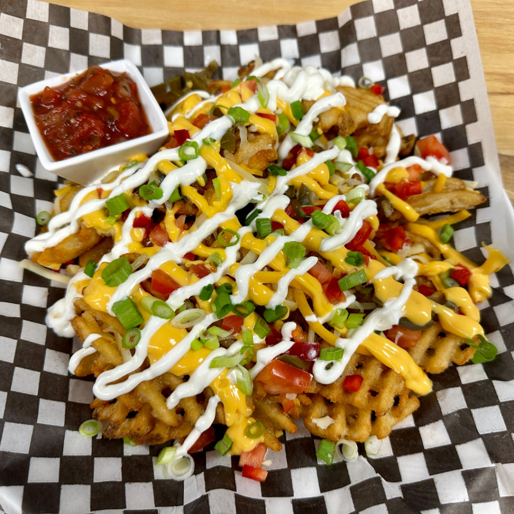 Loaded waffle fries served with a side of salsa.